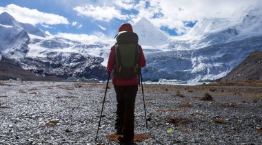 Kışın yüksek irtifa dağlarında yürüyüş yapan bir kadın.