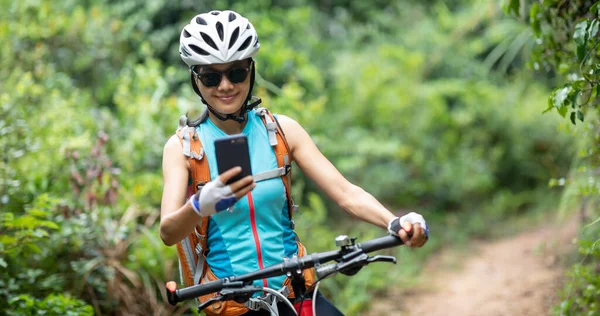 Radfahrerin Nutzt Smartphone Beim Mountainbiken Auf Waldweg — Stockfoto