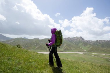 Sırt çantalı bir kadın yüksek irtifada dağ yürüyüşü yapıyor.