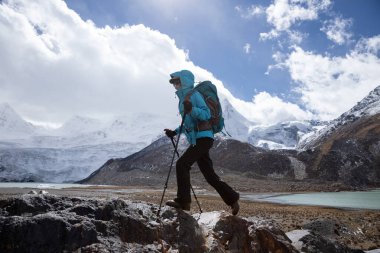 Yüksek rakımlı kış dağlarında yürüyüş yapan bir kadın.