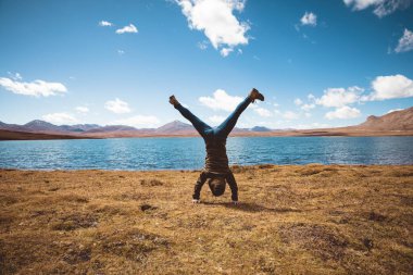 Göl kıyısındaki otlaklarda amuda kalkan insanlar