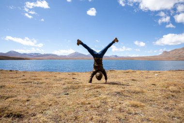 Göl kıyısındaki otlaklarda amuda kalkan insanlar