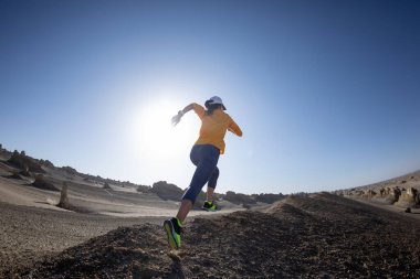 Fitness kadını, kum çölünde koşan bir koşucunun izini sürüyor.