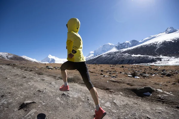 冬の山の中を走る女トレイルランナー — ストック写真