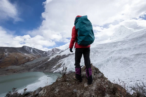 Successful woman backpacker hiking in winter mountains