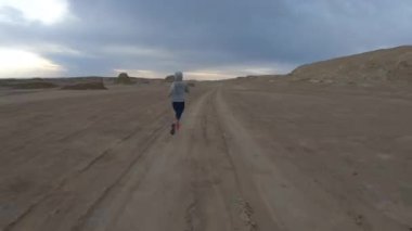 Çöl kum tepelerinde koşan genç bir kadın.