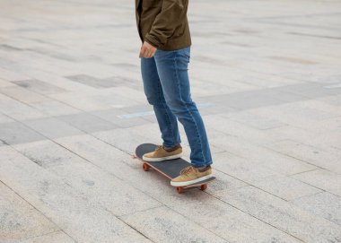 Kaykaycı güneşli bir sabahta dışarıda kaykay yapıyor.