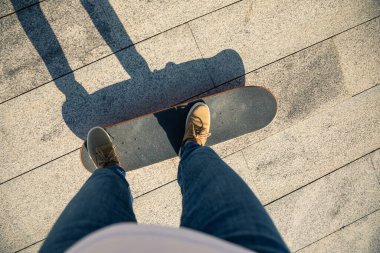 Kaykaycı güneşli bir sabahta dışarıda kaykay yapıyor.