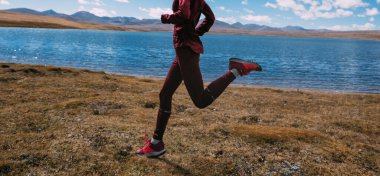 Kışın göl kenarında koşan kadın koşucu.