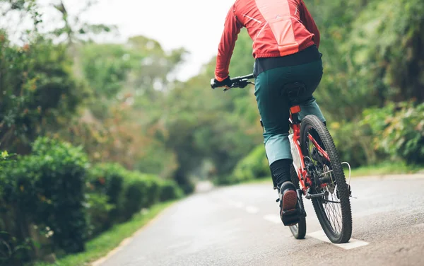 春に熱帯公園の歩道で自転車に乗る女性サイクリスト — ストック写真