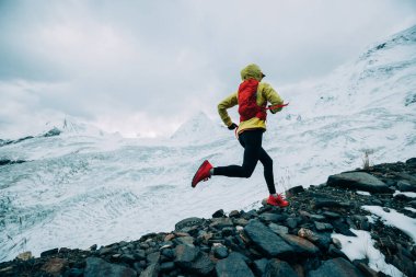Kadın koşucu kışın karlı dağlara doğru koşuyor.