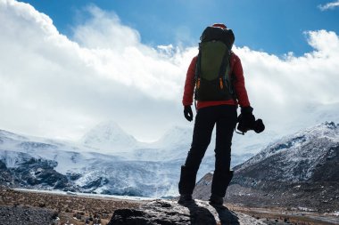 Yüksek irtifa dağlarında kameralı bir kadın yürüyüşçü.
