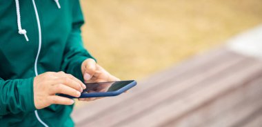 Açık havada akıllı telefon kullanan Asyalı kadın.