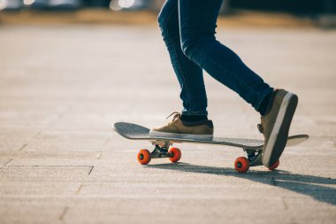 Kaykaycı güneşli bir sabahta dışarıda kaykay yapıyor.