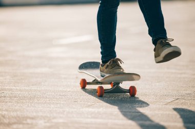 Kaykaycı güneşli bir sabahta dışarıda kaykay yapıyor.