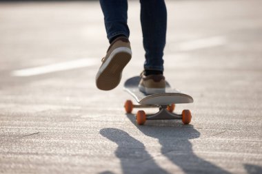 Kaykaycı güneşli bir sabahta dışarıda kaykay yapıyor.