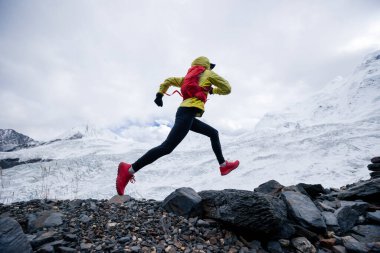 Kadın koşucu kışın karlı dağlara doğru koşuyor.