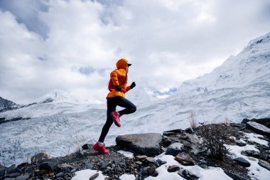 Kadın koşucu kışın karlı dağlara doğru koşuyor.