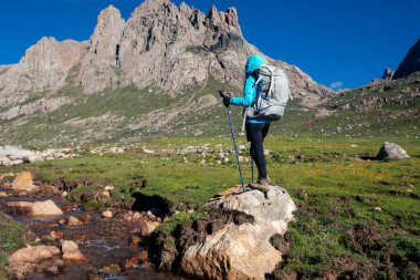 Sırt çantalı bir kadın yüksek rakım dağlarında yürüyüş yapıyor. 