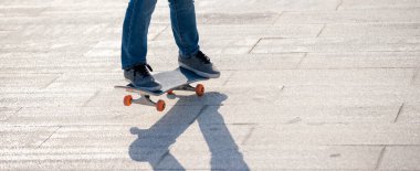 Kaykaycı güneşli bir sabahta dışarıda kaykay yapıyor.