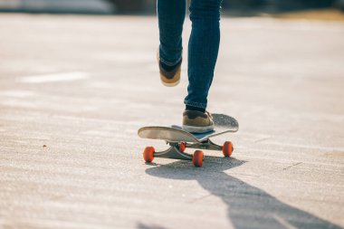 Kaykaycı güneşli bir sabahta dışarıda kaykay yapıyor.