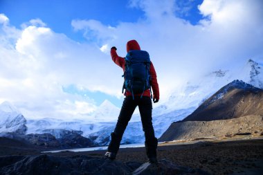 Kış dağlarında yürüyüş yapan güçlü bir kadın.