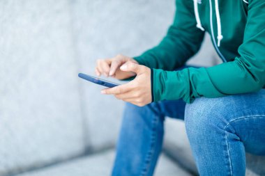 Açık havada akıllı telefon kullanan Asyalı kaykaycı kadın.