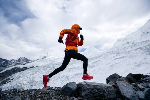 Kadın koşucu kışın karlı dağlara doğru koşuyor.