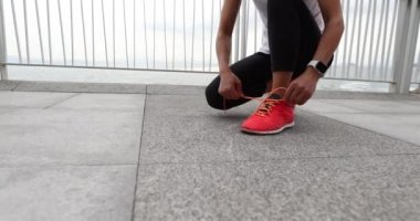 Park yolunda koşmadan önce ayakkabı bağcıklarını bağlayan kadın koşucu