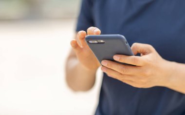 Açık havada akıllı telefon kullanan Asyalı kadın.