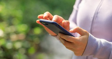 Açık havada akıllı telefon kullanan Asyalı kadın.