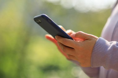 Açık havada akıllı telefon kullanan Asyalı kadın.