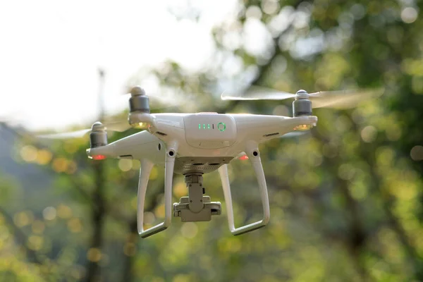 White drone with camera flying in spring tropical forest