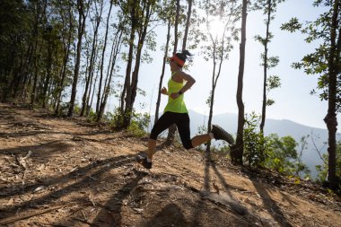 Gündoğumunda tropik orman zirvesinde koşan fitness kadın patika koşucusu