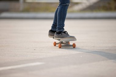 Kaykaycı bacakları açık havada kaykay yapıyor.