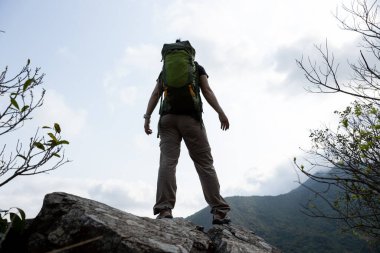 Dağların tepesinde duran kadın yürüyüşçü.