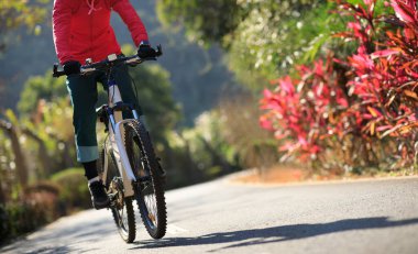 Baharda tropik park yolunda bisiklet süren bir kadın.