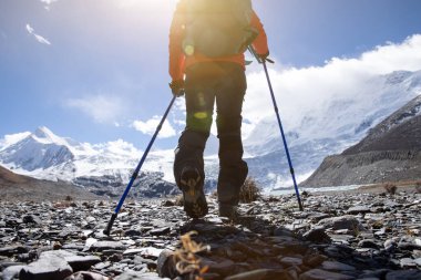 Yüksek rakımlı kış dağlarında yürüyüş yapan bir kadın.