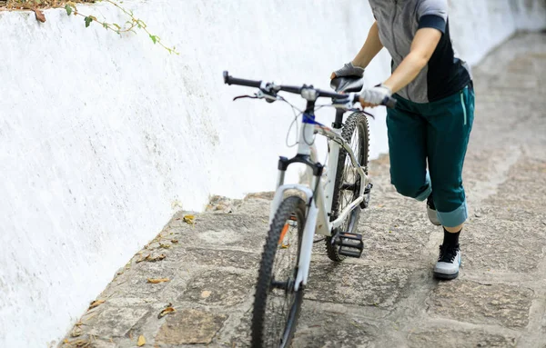 Woman freerider with mountain bike climbing up the stairs