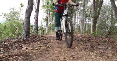 Bisikletli bir kadın ormanda bisiklet sürüyor.