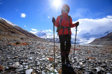 Yüksek rakımlı kış dağlarında yürüyüş yapan bir kadın.