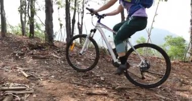 Bisikletli bir kadın ormanda bisiklet sürüyor.