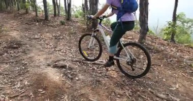 Bisikletli bir kadın ormanda bisiklet sürüyor.