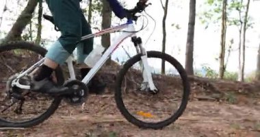 Bisikletli bir kadın ormanda bisiklet sürüyor.