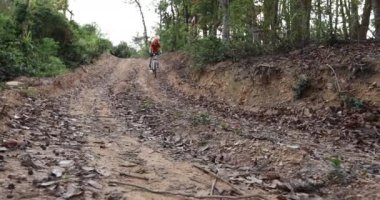 Bisikletli bir kadın ormanda bisiklet sürüyor.