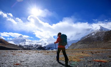 Yüksek rakımlı kış dağlarında yürüyüş yapan bir kadın.