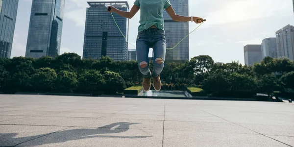 Fitness woman jumping rope on city