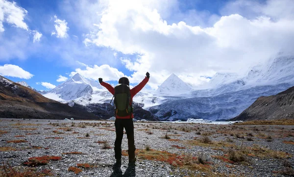 Successful woman backpacker hiking in winter mountains