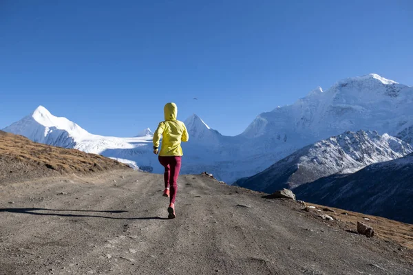 冬の山の中を走る女トレイルランナー — ストック写真