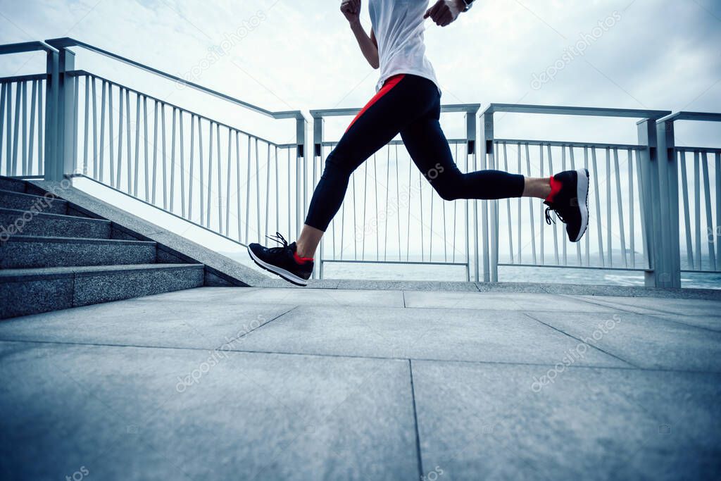 Healthy lifestyle fitness sports woman runner running up stairs on seaside trail